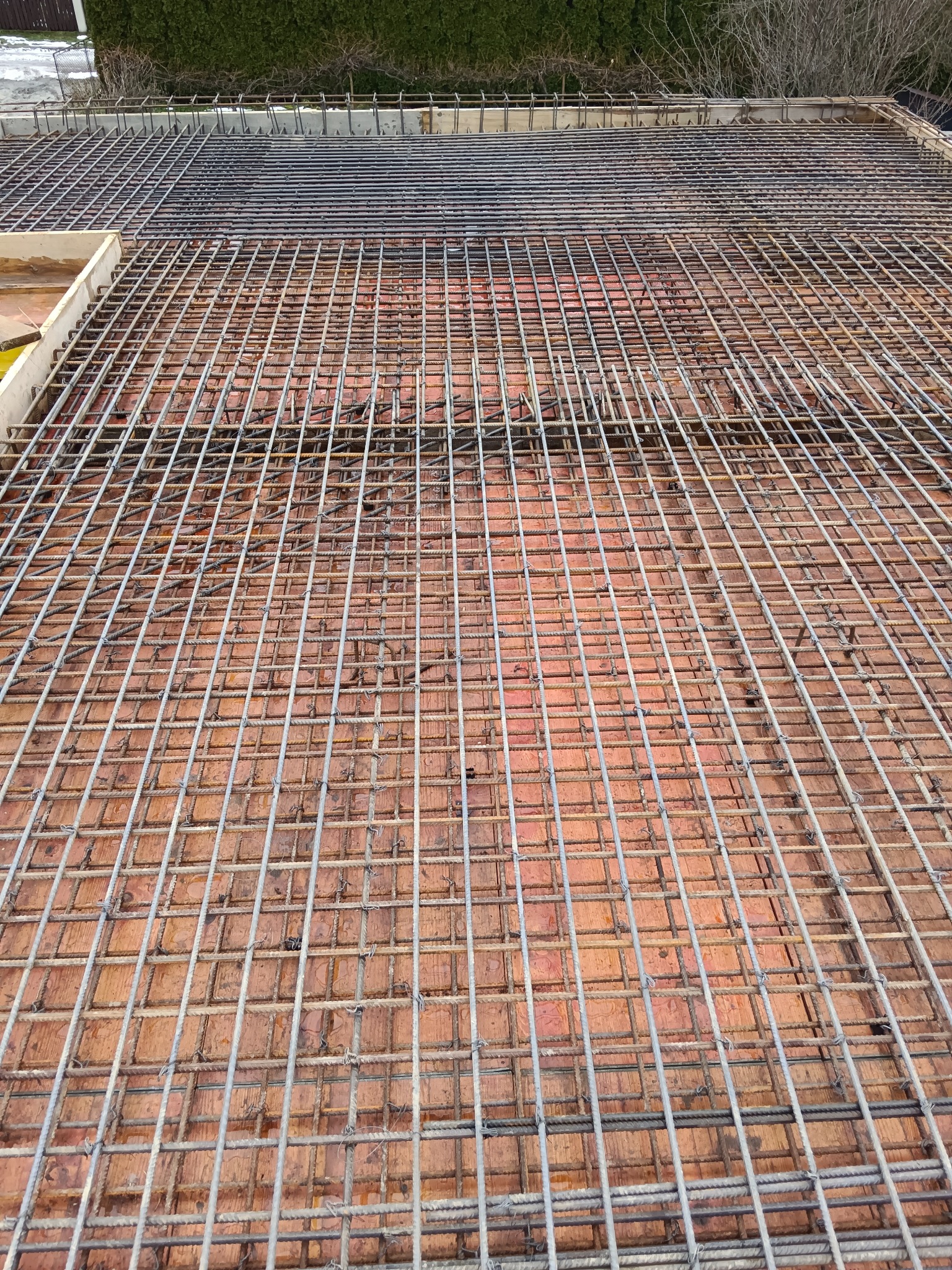 Zbrojenie stropu z widoczną siatką z prętów stalowych ułożoną na ceglanych pustakach. Widok z góry, ukazujący regularny układ konstrukcji.