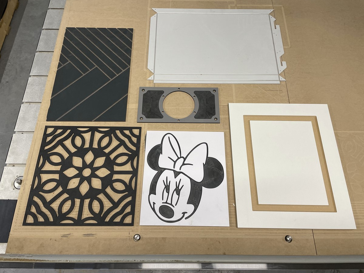 Elementy wycięte na ploterze CNC: dekoracyjne panele z wzorami geometrycznymi i kwiatowymi, ramka z MDF, obudowa i rysunek Myszki Minnie.