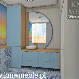Wizualizacja łazienki z niebieskimi szafkami, drewnianym blatem, okrągłym lustrem, tapetą z motywem żaglowca i wzorzystymi płytkami podłogowymi. Widoczne logo firmy KMWM Meble.