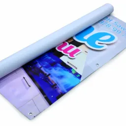 Zrolowany baner reklamowy z nadrukowanym zdjęciem wnętrza i elementami graficznymi, widoczne oczka do zawieszenia.