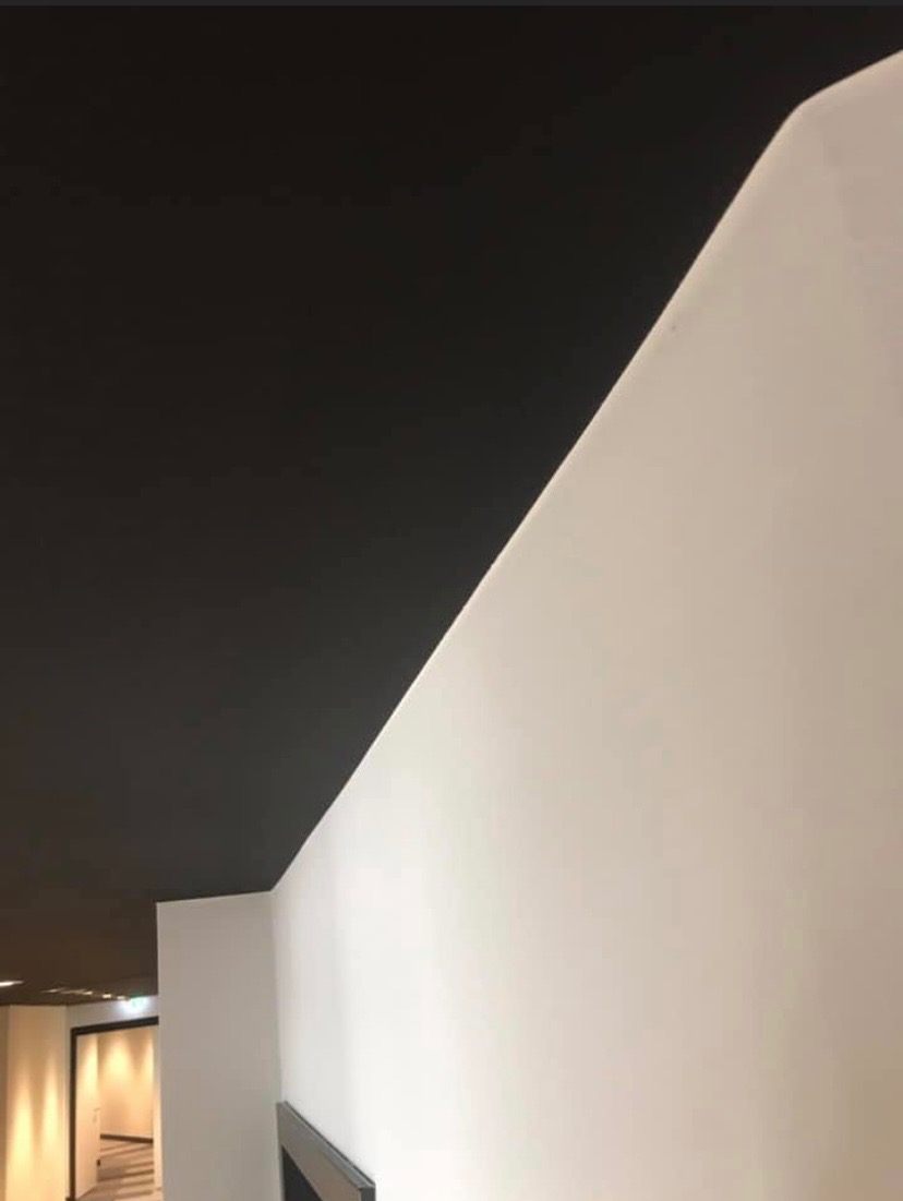 Pomieszczenie po remoncie: białe ściany kontrastują z czarnym sufitem, widoczny fragment korytarza w tle.