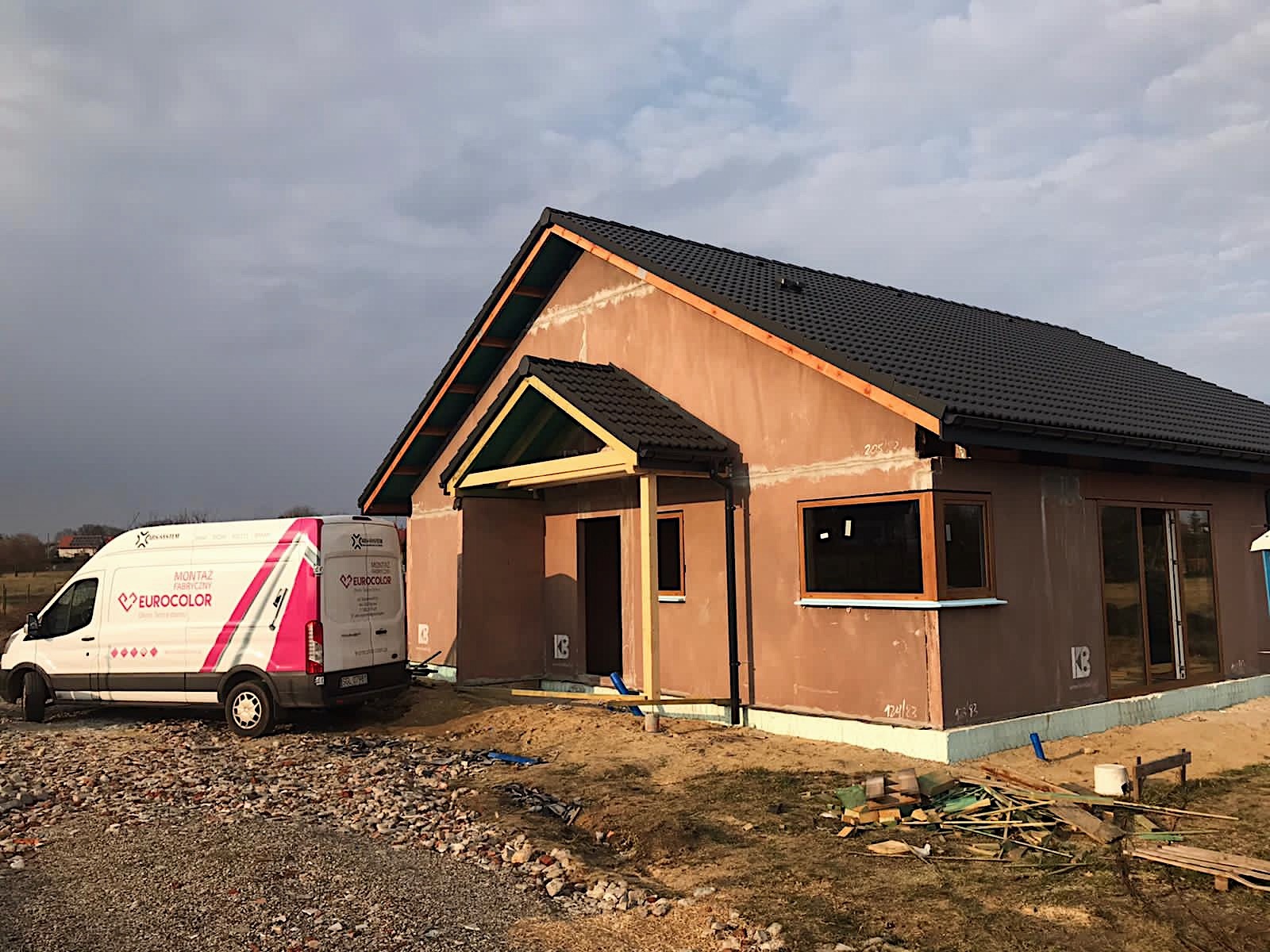 Dom jednorodzinny w trakcie montażu okien i drzwi przesuwnych, z widocznym samochodem firmowym z logo Eurocolor na posesji.