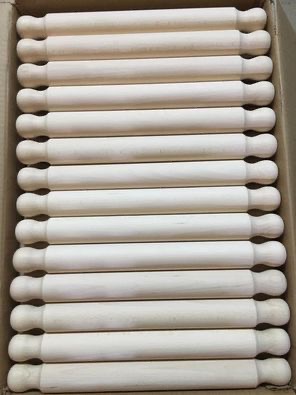 Rząd surowych, nielakierowanych, drewnianych wałków do ciasta w kartonowym pudełku, widoczne delikatne słoje drewna.