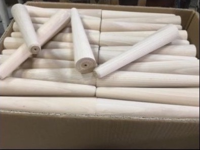 Partia surowych, stożkowych nóg meblowych z jasnego drewna, przygotowanych do dalszej obróbki, widoczne otwory montażowe na górze.