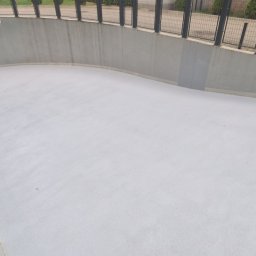 Epoxy3D - Jasnoszara, gładka powierzchnia posadzki w zagłębieniu, otoczona betonową ścianą i metalową balustradą, widok z góry.