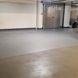 Epoxy3D - Szara posadzka żywiczna w garażu podziemnym, widoczne żółte słupy i motocykl w tle.