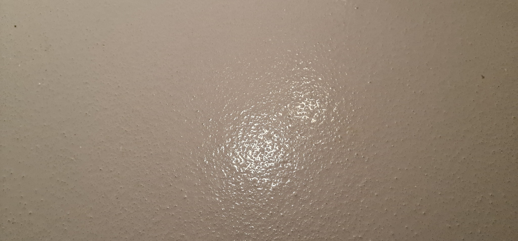 Szczegółowe ujęcie beżowej powierzchni z wyraźną, nierównomierną fakturą, charakteryzującą się drobnymi wypukłościami i refleksami światła.
