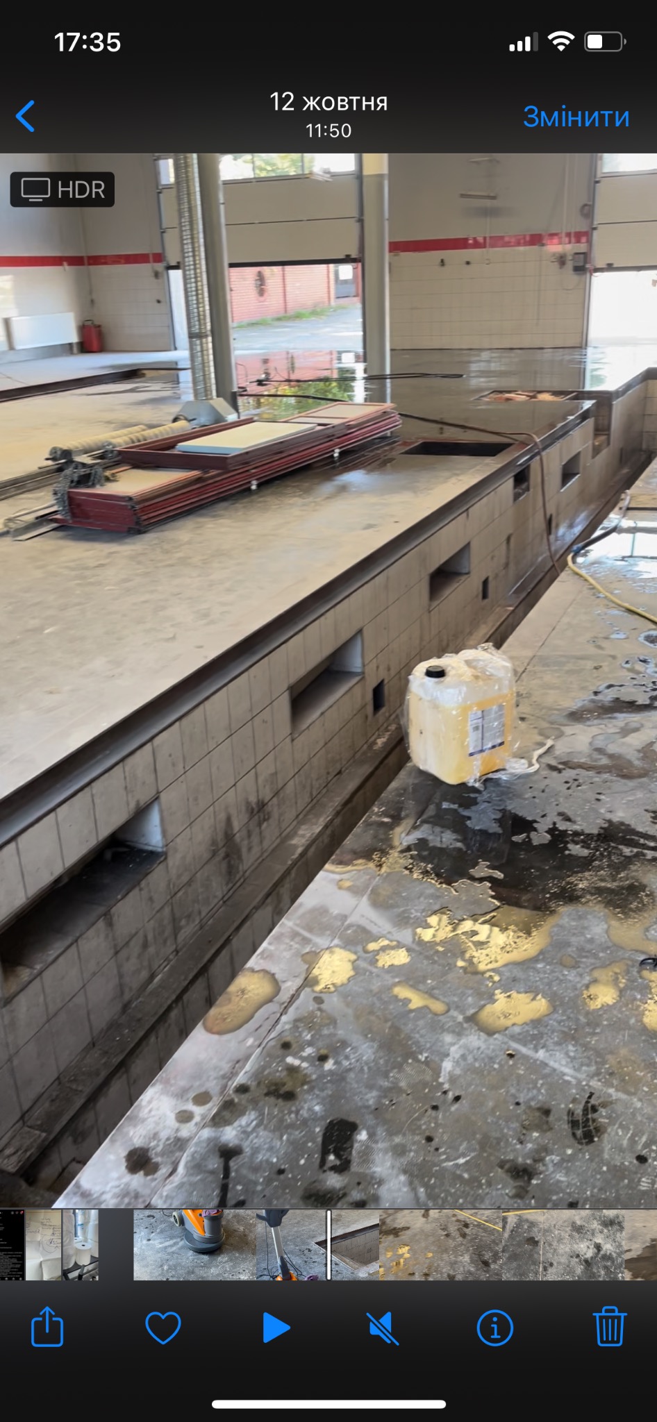 Wnętrze hali po umyciu, widoczne mokre plamy na posadzce, biało-żółty kanister z płynem czyszczącym oraz złożone metalowe elementy konstrukcyjne.