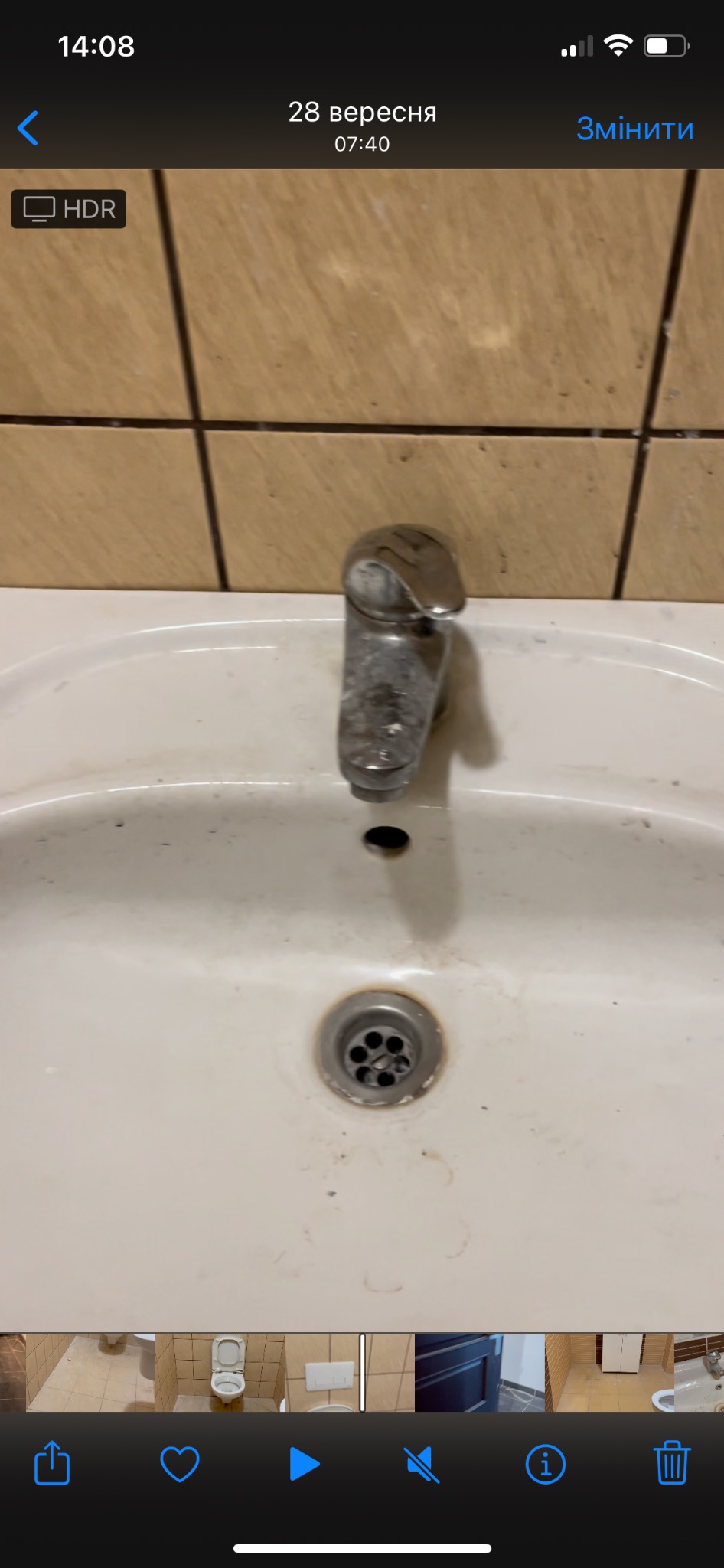 Zanieczyszczona umywalka z metalową baterią, widoczne plamy i osad, brudne płytki w tle.