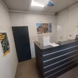 Wnętrze recepcji warsztatu samochodowego z plakatem opon Fulda, plakatem offroadowym, i lampą sufitową w kształcie sterowca Goodyear