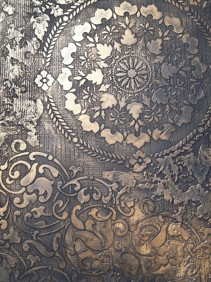 Dekoracyjna ściana z efektem metalicznego reliefu i motywami roślinnymi, w odcieniach złota i szarości, z widoczną fakturą i detalami ornamentów.