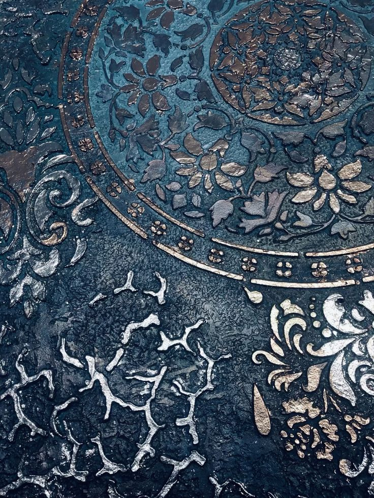 Dekoracyjna ściana w odcieniach granatu z reliefami kwiatowymi i geometrycznymi w kolorze srebrnym i złotym, imitująca metaliczny ornament.