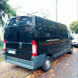 Czarny bus dostawczy zaparkowany na ulicy z opadłymi liśćmi, widok z tyłu, tablica rejestracyjna EP 6137C widoczna.