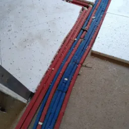 Czerwone i niebieskie rury ogrzewania podłogowego w izolacji, ułożone w wykopie w podłodze, przed wylaniem wylewki.