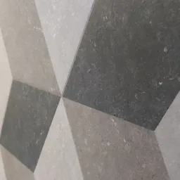 Ułożona pod kątem podłoga z płytek w odcieniach szarości i bieli, tworząca iluzję trójwymiarowości.