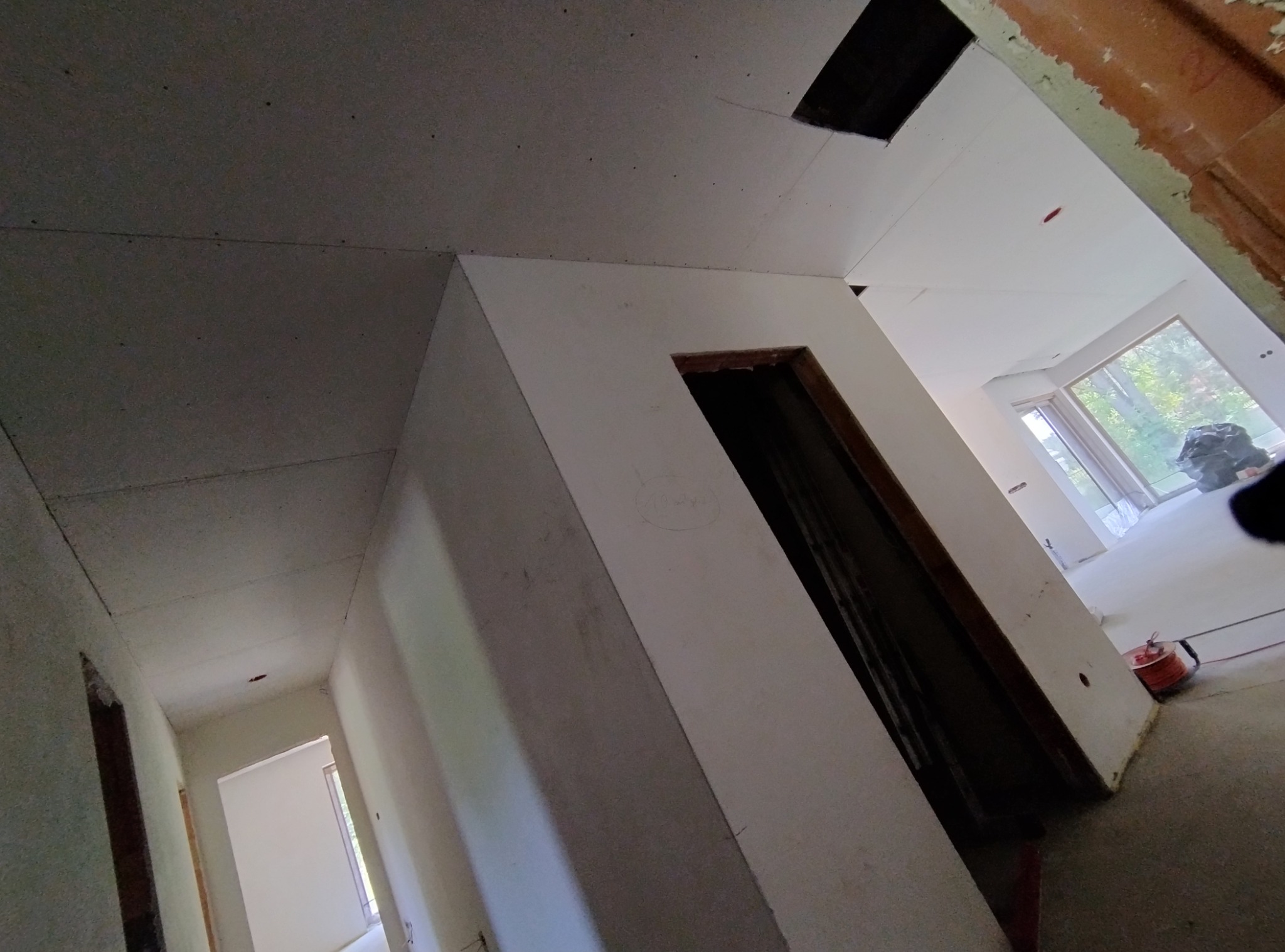 Wnętrze w trakcie montażu płyt kartonowo-gipsowych na suficie, widoczne łączenia i fragmenty konstrukcji, surowy stan wykończenia.