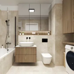 Jasna łazienka z wanną, umywalką na szafce z drewnianym frontem i toaletą. W tle szafki i pralka. Minimalistyczny design, beżowe płytki imitujące marmur.