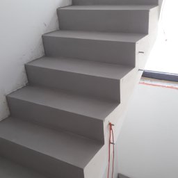 Liubomyr Ovchar - Schody betonowe w szarym odcieniu, świeżo wykończone, z widocznymi metalowymi elementami mocującymi i pomarańczowym kablem zwisającym wzdłuż ściany, w surowym stanie.