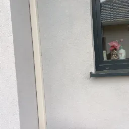 Zewnętrzna jednostka klimatyzacji Rotenso Ukura zamontowana na elewacji budynku, z widocznymi rurami odprowadzającymi i oknem w tle.