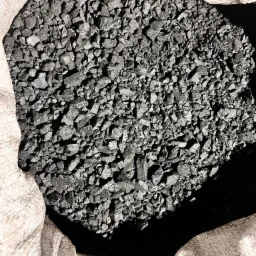 Worek jutowy wypełniony czarnym ekogroszkiem, widoczne nieregularne bryłki węgla o matowej powierzchni.