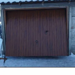 Brązowa brama garażowa segmentowa z dwoma zamkami na tle ośnieżonego dachu i podjazdu.