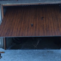 Jag-Woj - Otwarta, brązowa brama garażowa segmentowa z dwoma uchwytami, widok na wnętrze garażu w zimowy dzień, śnieg na dachu i przed garażem.