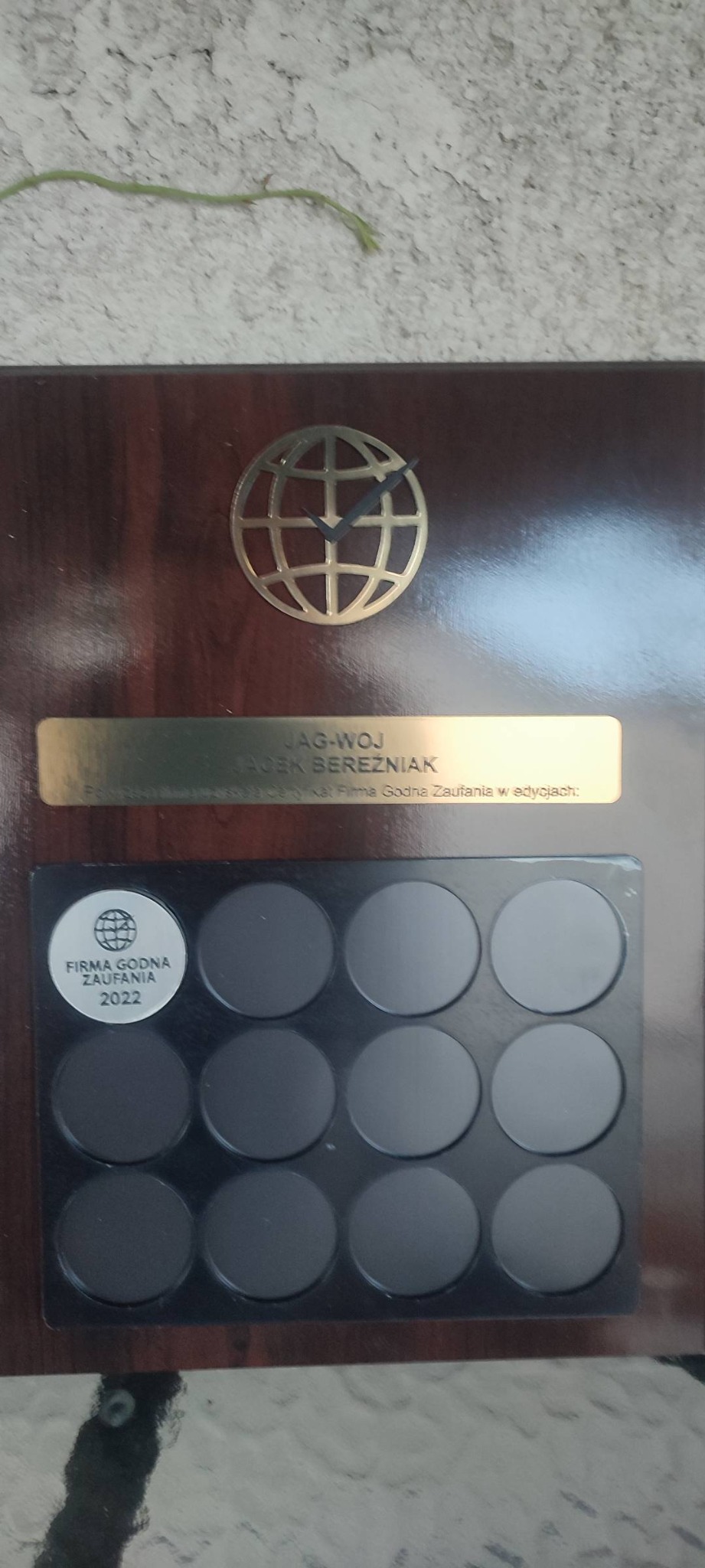 Drewniana tablica z logo firmy JAG-WOJ Jacek Bereźniak, posiadającej certyfikat Firma Godna Zaufania z okrągłym emblematem Firma Godna Zaufania 2022 i miejscami na kolejne lata certyfikacji.