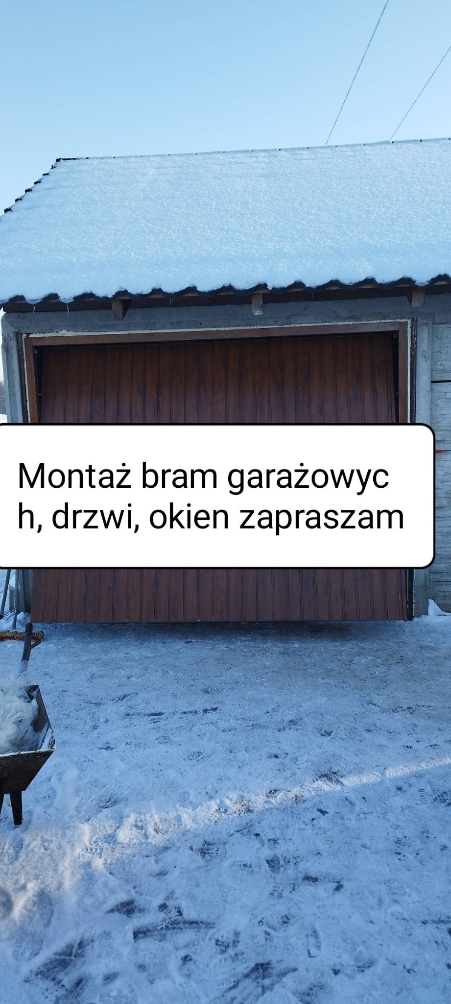 Zimowy widok na garaż z drewnianą bramą segmentową; śnieg pokrywa dach i podłoże.
