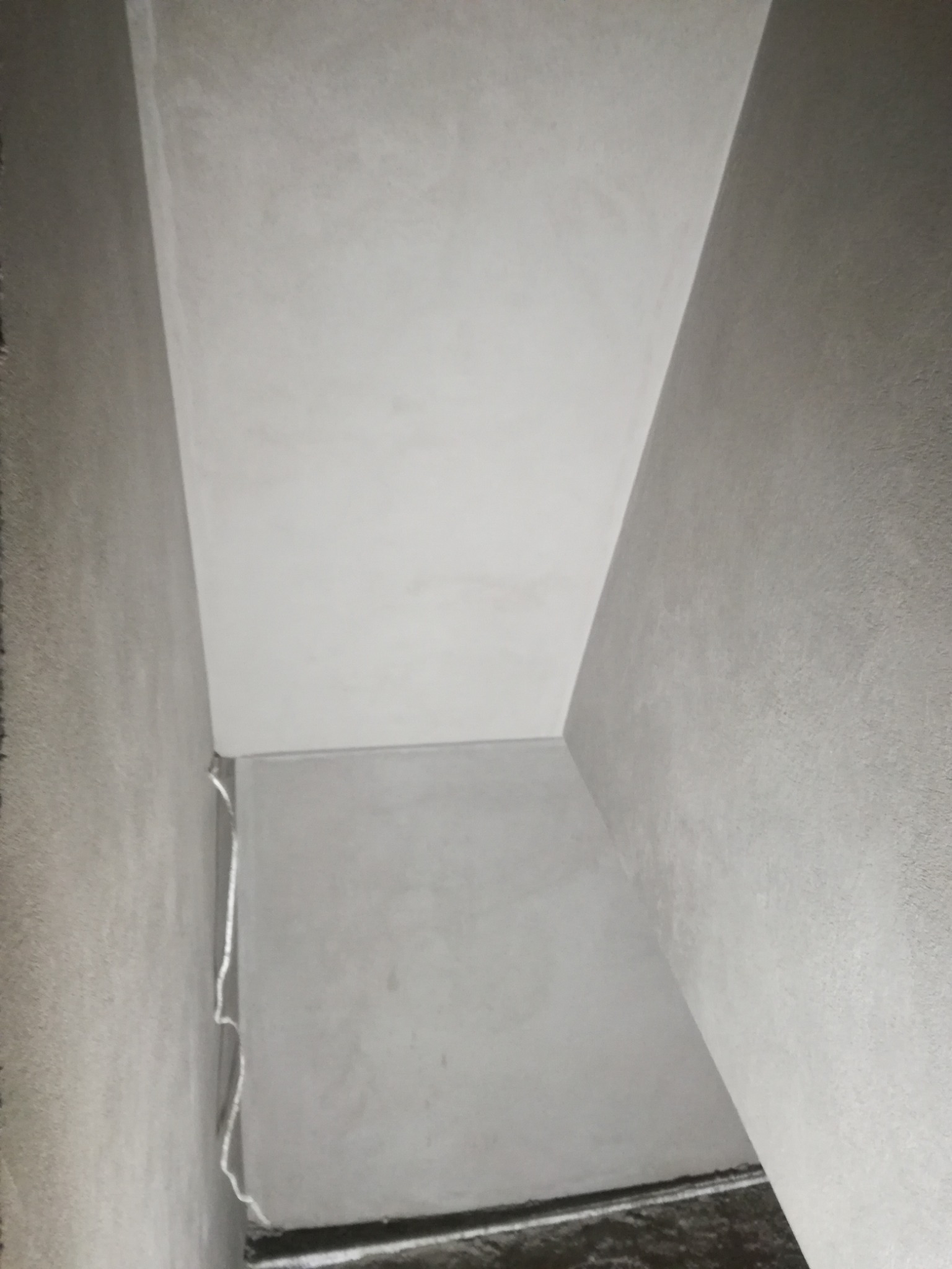 Wnętrze w Grodzisku Wielkopolskim po nałożeniu szarej warstwy wykończeniowej na ścianach i suficie, widoczne niedoskonałości w narożniku i przy podłodze.