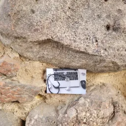 Laptop z myszką i stetoskopem leżący na kartce papieru na tle kamiennej ściany.