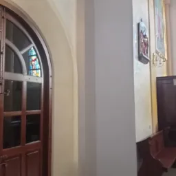 Jasne wnętrze z łukowym wejściem, drewnianą ławką i obrazami na ścianie, świeżo po odnowieniu.