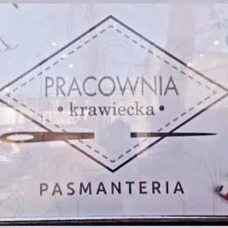 Witryna pracowni krawieckiej z napisem 'Pracownia krawiecka Pasmanteria' ozdobiona rysunkami igły, nici i guzików.
