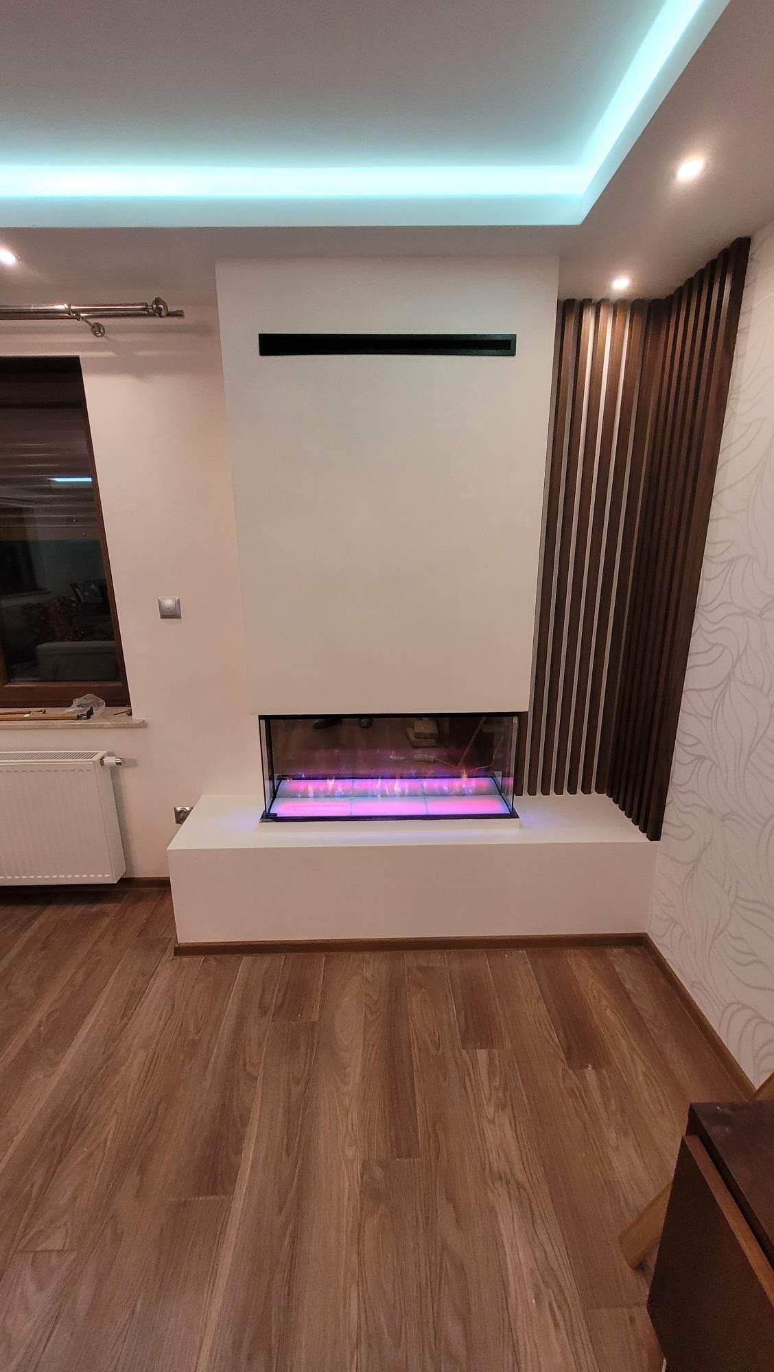 Nowoczesny biokominek w zabudowie z płyt kartonowo-gipsowych, obok dekoracyjna ściana z drewnianych listew, na podłodze panele.