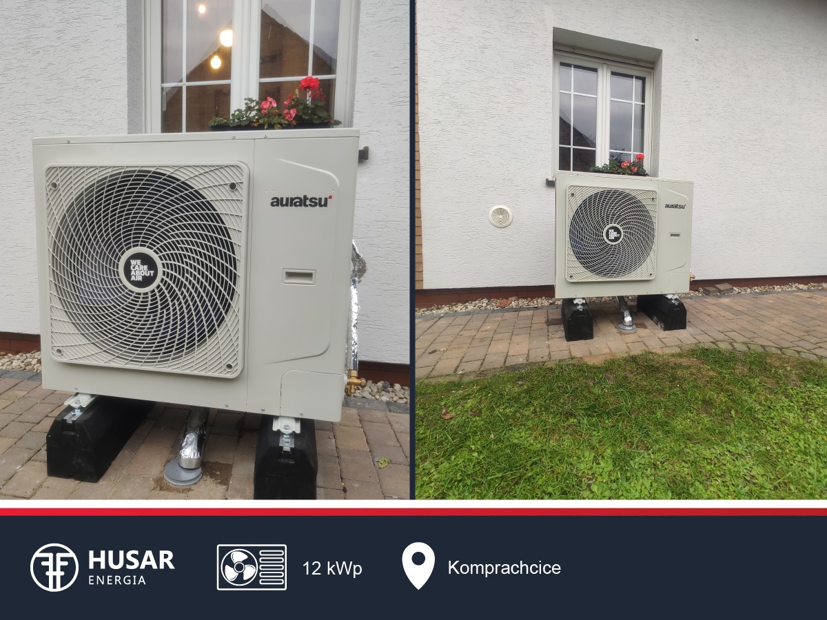 Zewnętrzna jednostka pompy ciepła Auratsu zamontowana na czarnych blokach betonowych przy jasnej elewacji domu z oknem ozdobionym kwiatami.