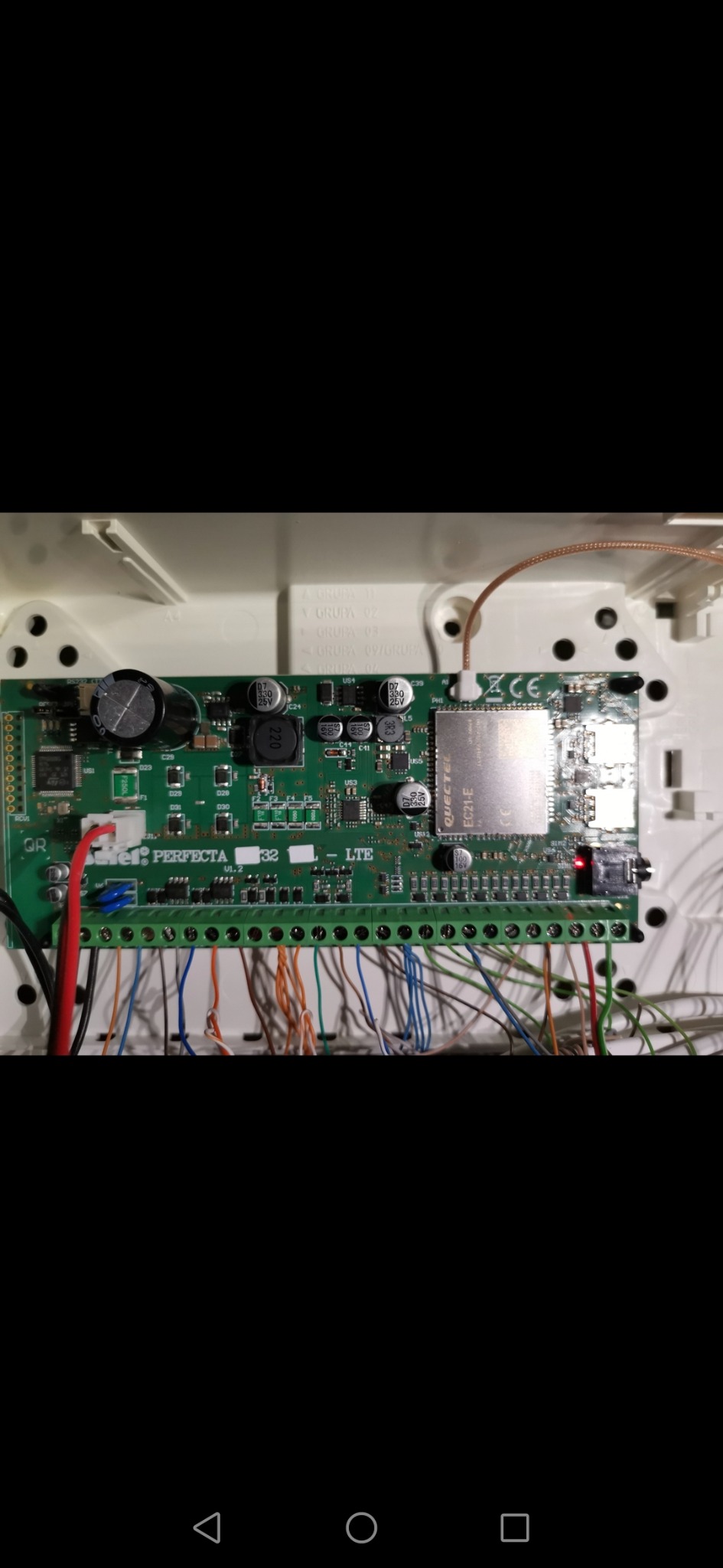 Centrala alarmowa Perfecta 32 LTE z podłączonymi przewodami, widoczne elementy elektroniczne i złącza śrubowe.