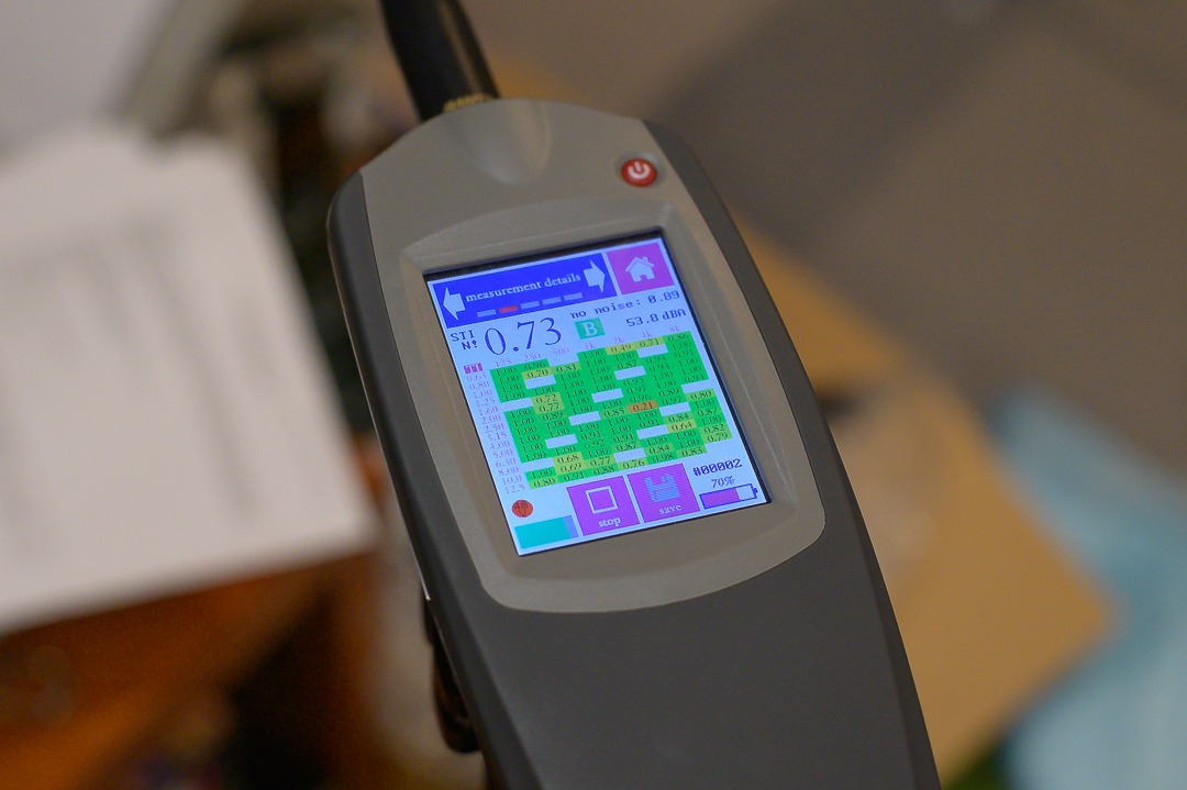 Urządzenie do pomiaru zrozumiałości mowy DSO z wyświetlaczem prezentującym wyniki pomiarów w formie tabeli z wartościami numerycznymi i kolorowymi oznaczeniami.