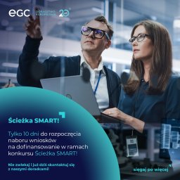 EGC Doradztwo Europejskie - Dwoje doradców w okularach, mężczyzna z laptopem wskazuje palcem, kobieta patrzy w tym samym kierunku, firmowe logo EGC w tle.