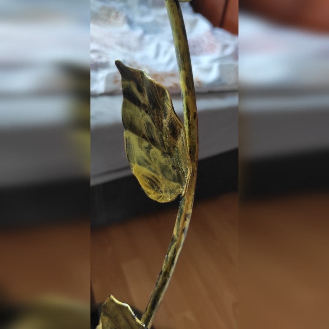 Metalowa roślina z liściem po procesie łączenia elementów, widoczne ślady obróbki termicznej i łączenia.