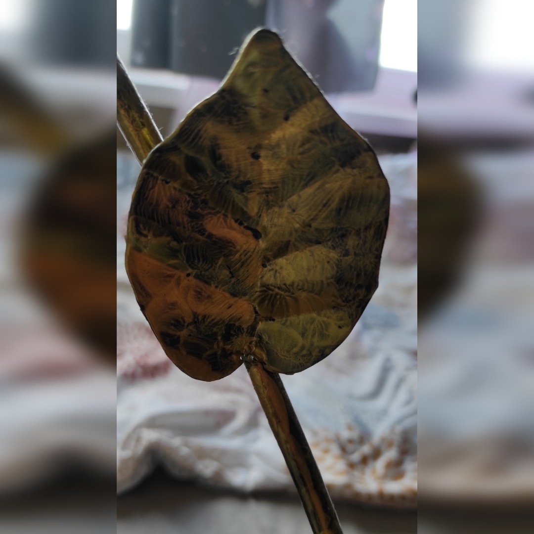 Metalowa ozdoba w kształcie liścia z widocznymi śladami spawania, imitująca naturalną strukturę liścia.