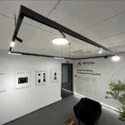 Salon z systemem inteligentnego budynku Ampio, prezentujący panele dotykowe, aplikacje i rozwiązania dla hoteli, deweloperów, biur, restauracji i przemysłu, z nowoczesnym oświetleniem szynowym...
