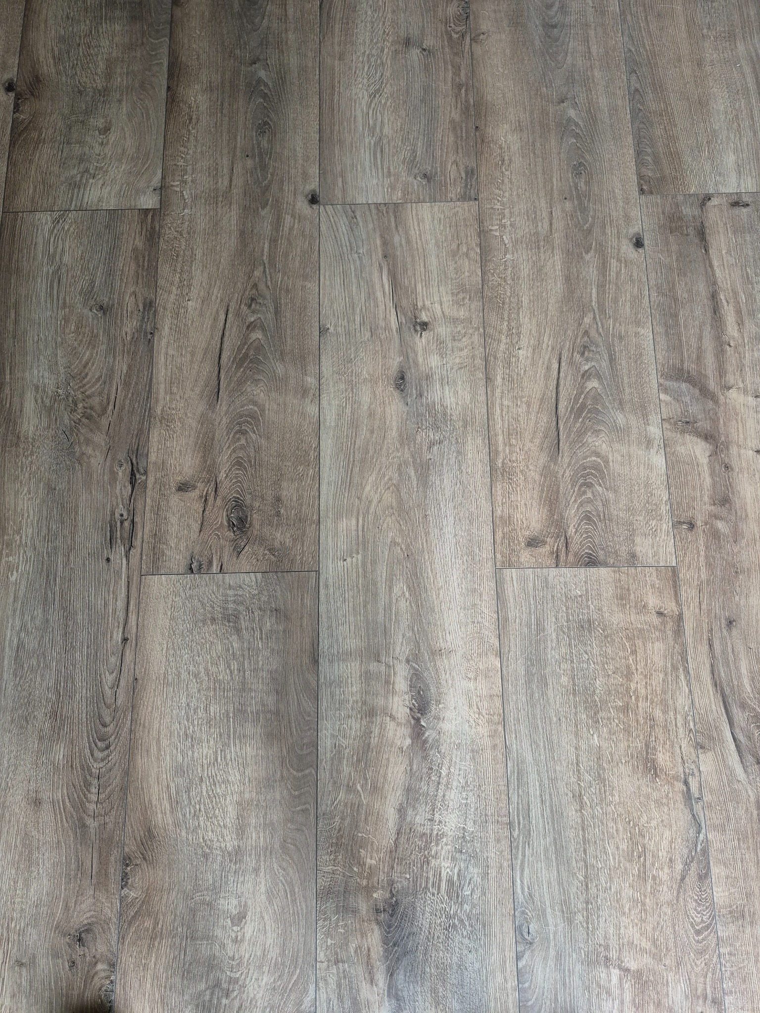 Ułożone panele podłogowe w odcieniach szarości z wyraźną strukturą drewna, widoczne łączenia między panelami, perspektywa z góry.