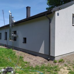 GENERAL-BUD Piotr Porczyński - Elewacja budynku jednorodzinnego po ociepleniu, z widocznym kominem ceramicznym i stalowym systemem odprowadzania spalin, antena telewizyjna na dachu.
