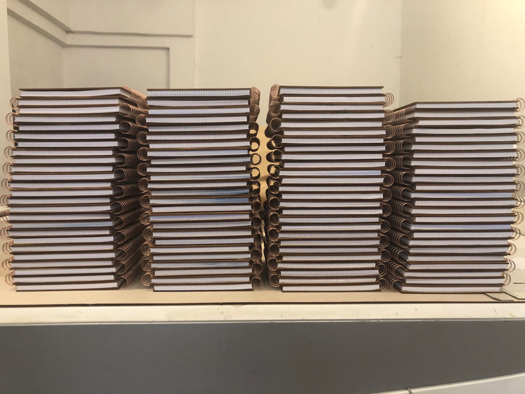 Stosy identycznych notesów z brązową okładką i metalową spiralą, przygotowane jako upominki firmowe w Częstochowie.