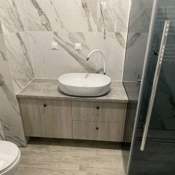 SZWAGRY DESIGN meble z pasją - Nowoczesna łazienka z umywalką nablatową na szafce z szufladami, kabina prysznicowa w tle, marmurowe płytki na ścianach i podłodze.