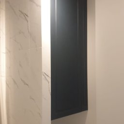 Wykonano szafkę wnękową w łazience, ponad pralką - front płyta lakierowana, frezowana mat. 