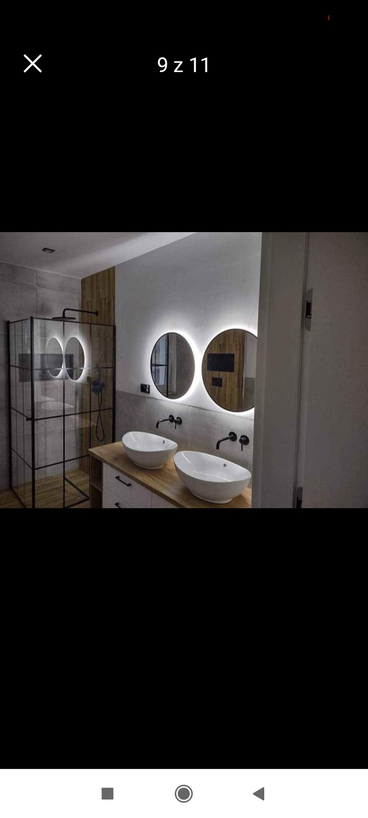 Nowoczesna łazienka z dwoma owalnymi umywalkami nablatowymi, czarną armaturą i okrągłymi lustrami z podświetleniem LED, kabina prysznicowa w stylu loft z czarnymi profilami.