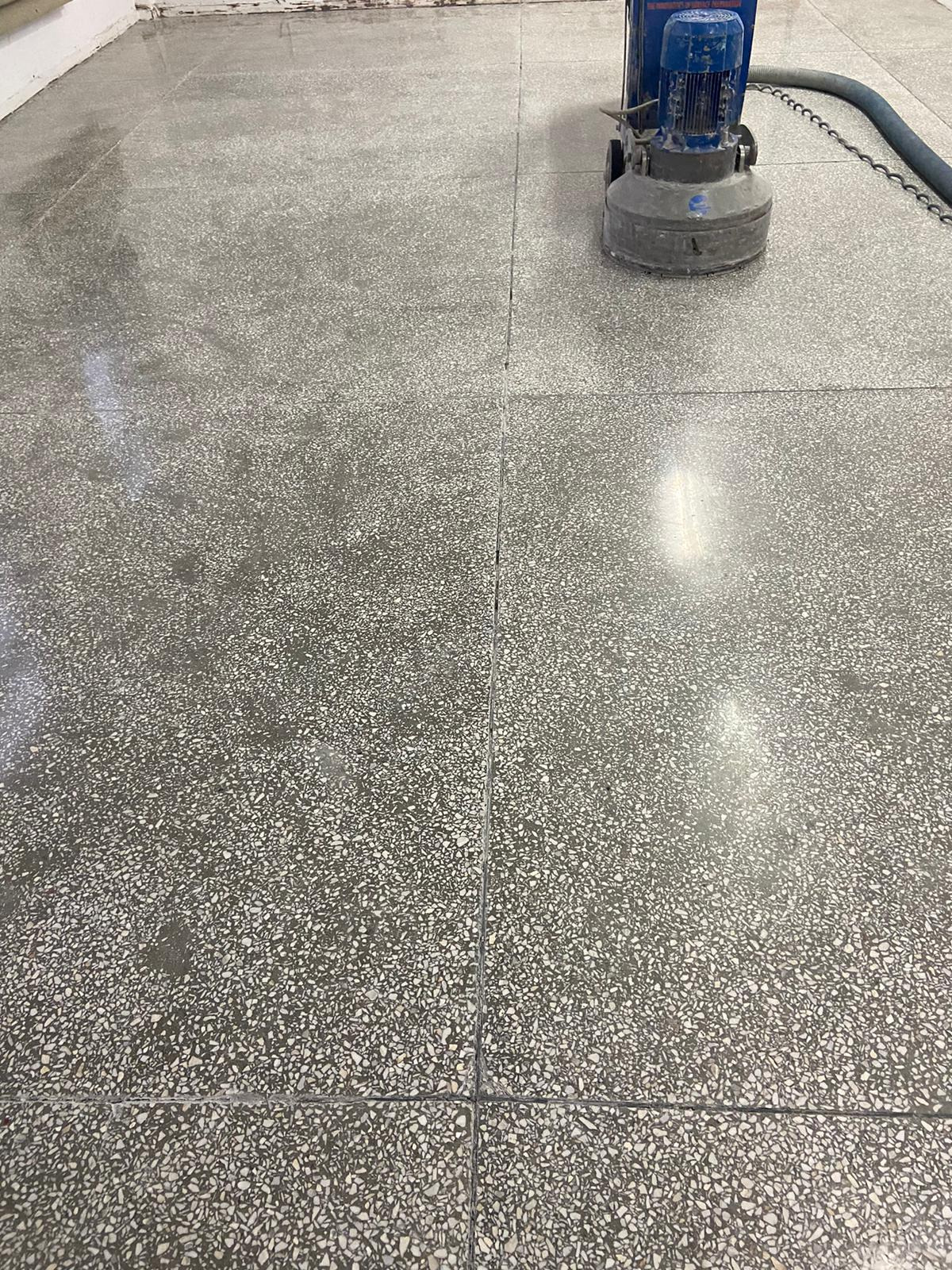 Szlifowanie posadzki lastryko za pomocą profesjonalnej szlifierki. Widoczny efekt polerowania i odkurzania, pozostawiający gładką powierzchnię.