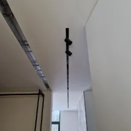 Montaż sufitu podwieszanego z płyt karton gips z widoczną konstrukcją metalową i oświetleniem punktowym w nowoczesnym wnętrzu.