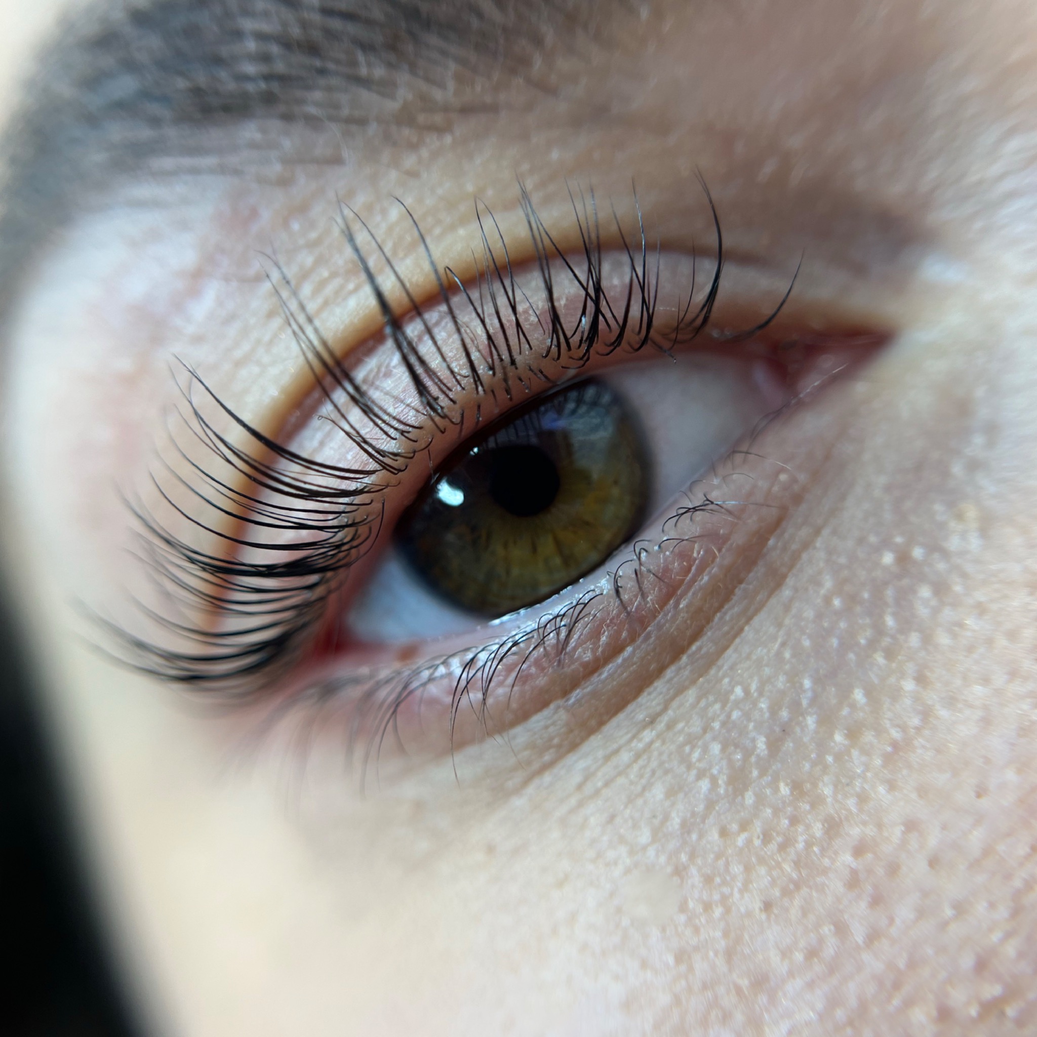 Zbliżenie na oko z widocznymi, przedłużonymi rzęsami, podkreślającymi zielono-brązową tęczówkę.