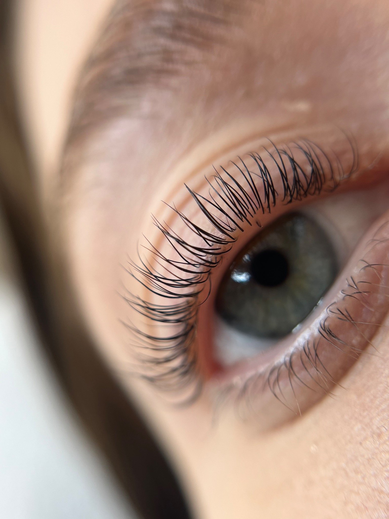 Zbliżenie na oko z przedłużonymi, czarnymi rzęsami, widoczne delikatne, zielone zabarwienie tęczówki.
